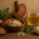 Heilpflanzen und Hausmittel bei Gastritis: Kamille, Fenchel, Leinsamen, Heilerde und Magen-Symbol auf Holztisch.
