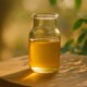Glasfläschchen mit goldener Colostrum-Flüssigkeit auf einem Holztisch im warmen Sonnenlicht, mit sanft unscharfem, natürlichen Hintergrund.